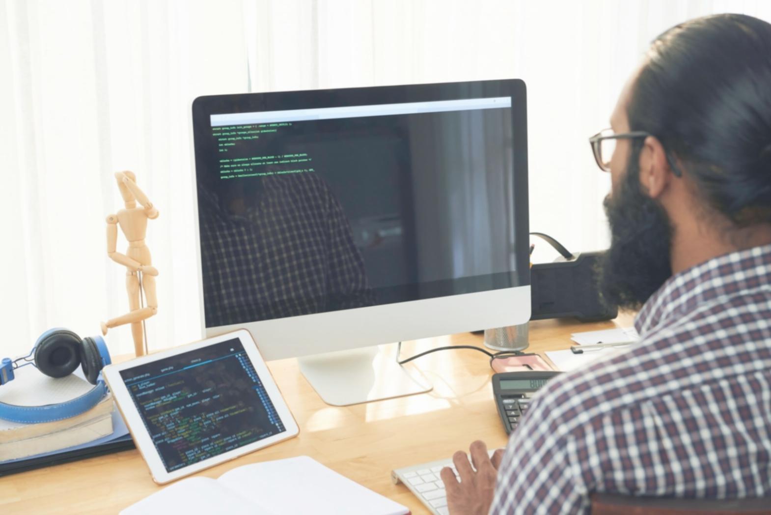 Development team collaborating on mobile app architecture with laptops and design mockups